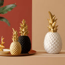 Golden resin ornament designed in the shape of a pineapple, displayed on a table alongside a vase and plant, emphasizing its use in Nordic home decor.