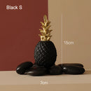 Golden resin ornament in the shape of a pineapple, displayed in a black vase, suitable for Nordic home decor.
