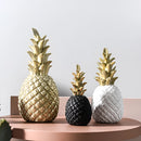 Golden resin ornament designed to resemble a pineapple, featuring natural material textures and set against a wooden background.