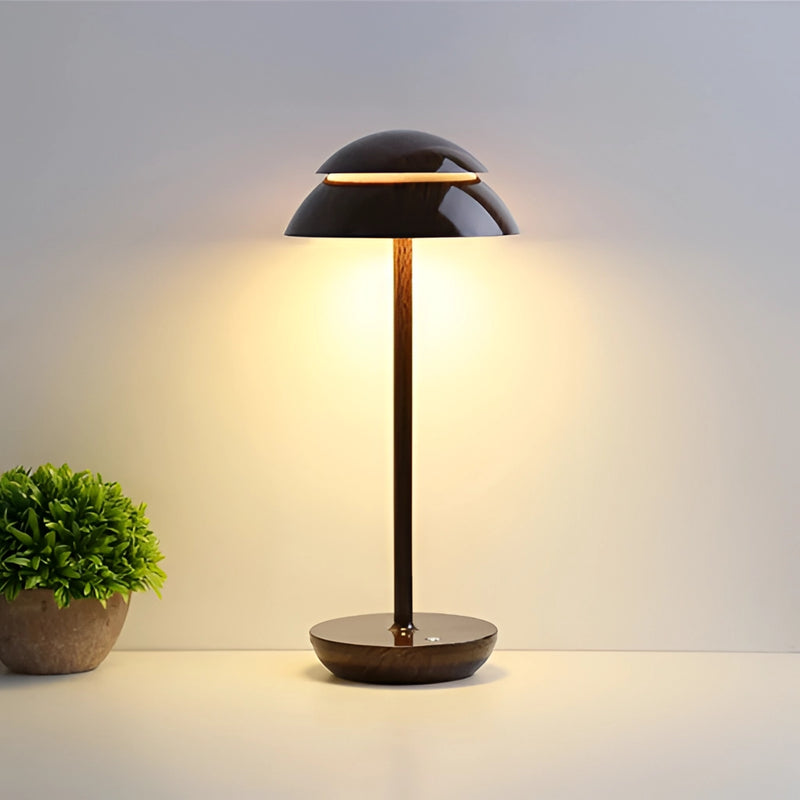 Scandinavian design table lamp with a walnut base, featuring a rectangular lampshade and artistic tints and shades, placed on a wooden floor near a plant in a flowerpot.