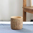 Small rattan cement planter with natural texture, displayed on a wooden table without a tray.