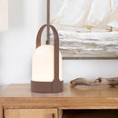 Rechargeable table lamp with touch dimming feature, placed on a wooden table next to textile and various bags.