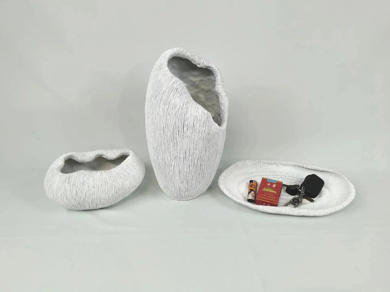 Decorative resin bowl inspired by nature, featuring grey and carmine tones, displayed on a wooden floor with artistic rock elements around it.