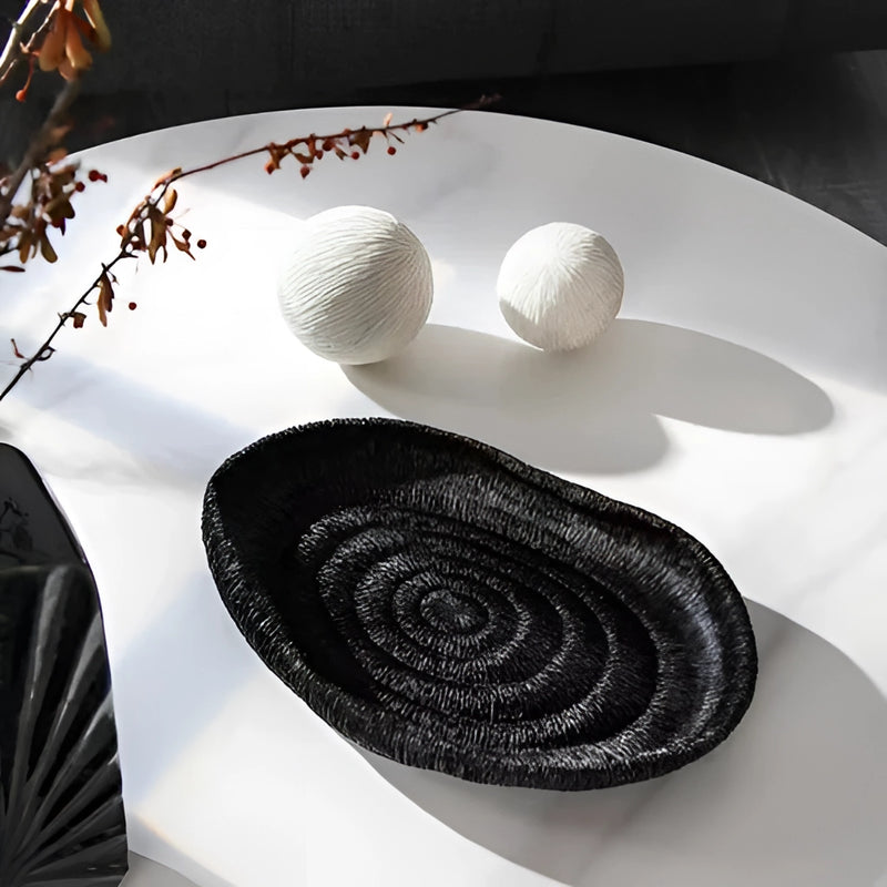 Decorative resin bowl inspired by nature, displayed on a table, predominantly grey in color with intricate art designs, resembling both serveware and textile elements.