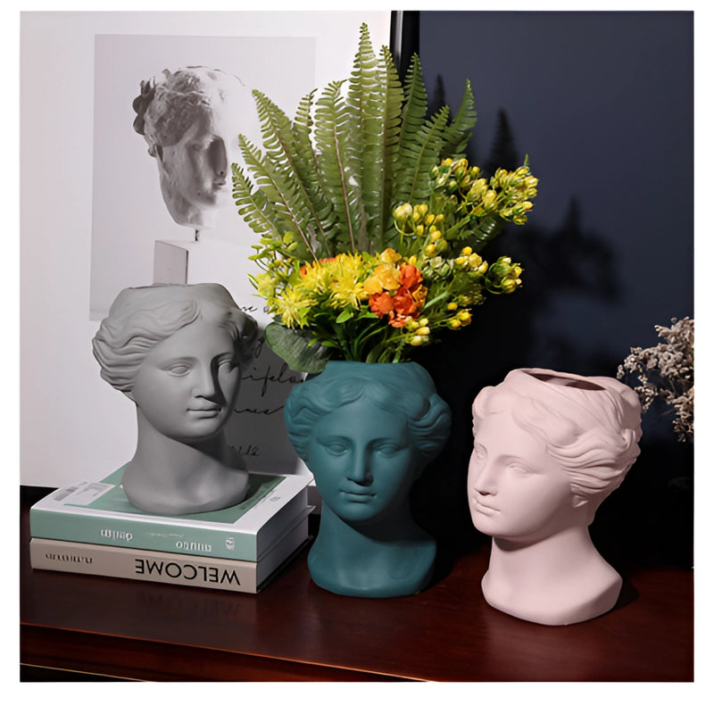 Neoclassical resin Venus vase featuring a sculptural head design, adorned with plants and flowers, available in blush pink, teal, and grey colors.