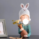 Resin table lamp featuring a white elegance rabbit girl figurine with dual glass lampshades, dressed in a costume with a hat, sitting beside a picture frame.