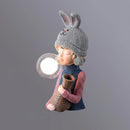 Resin table lamp featuring an elegant rabbit girl design with a dual glass lampshade, detailed costume hat, and artistic patterns on a wooden base, in grey, dimensions Ø 3.1″ x W 5.1″ x H 12.2″.