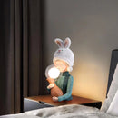 Elegant resin table lamp featuring a rabbit girl design with dual glass lampshades, set in a cozy room with wooden accents and curtains near a window.