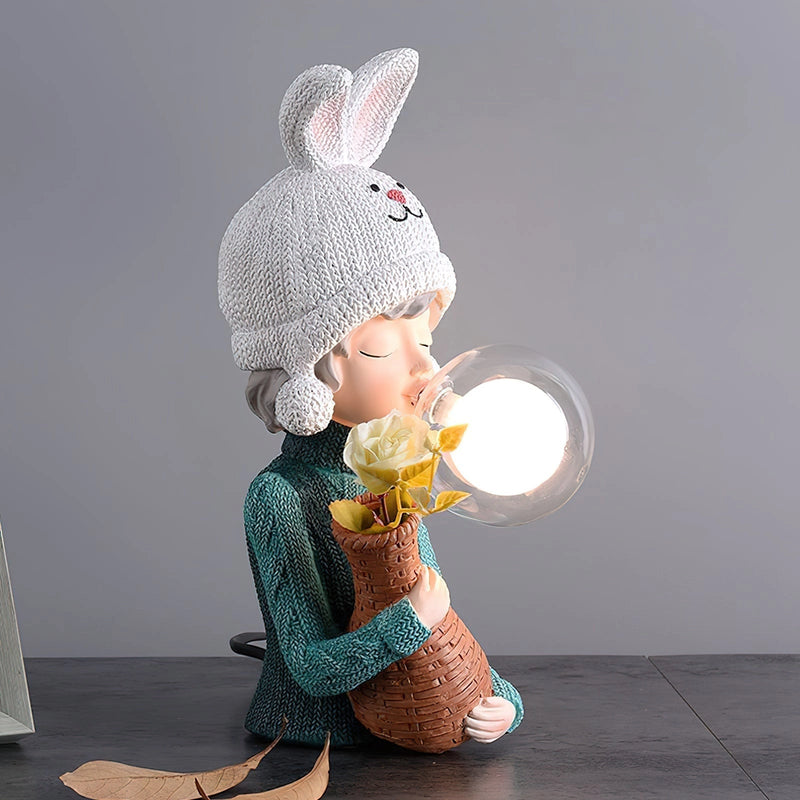 Resin table lamp featuring the design of a rabbit girl doll wearing a knit cap and costume hat, sitting with a happy expression and dual glass lampshades.