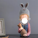 Resin table lamp featuring a rabbit girl design with a dual glass lampshade, adorned with textured textiles and wood accents.
