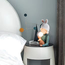 Resin table lamp designed as an elegant rabbit girl with dual glass lampshades, featuring artistic and animated design elements in a room setting.