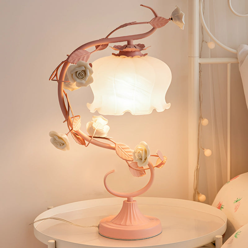 Elegant table lamp featuring a rose encased design with ornamental twigs, set on a wooden table under a chandelier.