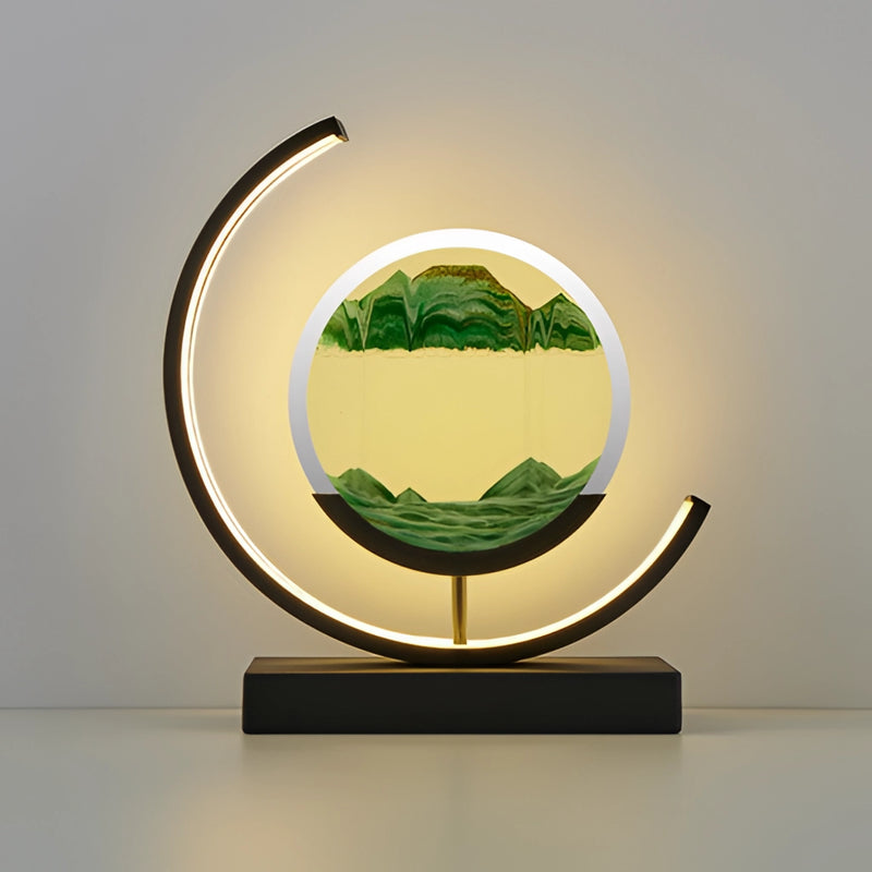 Dynamic 3D sand painting light featuring a green and black Sand Art LED Table Lamp, designed with various artistic symbols and emblems, set against a grass-like background.