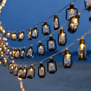 RGB and white colored solar string lights with LED lanterns, waterproof and displayed outdoors, giving off an amber light.