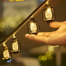 Solar string lights featuring outdoor LED lanterns, available in RGB and white colors, displayed on a wooden surface with amber lighting and glass accents, emphasizing their IP65 waterproof quality.