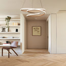 Spiral pendant light hanging in a modern interior with warm illumination, featuring wood flooring and beige hall decor.