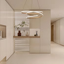 Modern spiral pendant light with warm illumination hanging in an elegant interior featuring wooden flooring and plant decor.