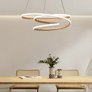 Modern spiral pendant light in an elegant design, casting a warm illumination over a stylish interior featuring a wooden table, houseplants in flowerpots, and white walls.