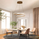 Spiral pendant light hanging above a wooden table in a room with elegant furniture, plants, and a window, providing warm illumination.