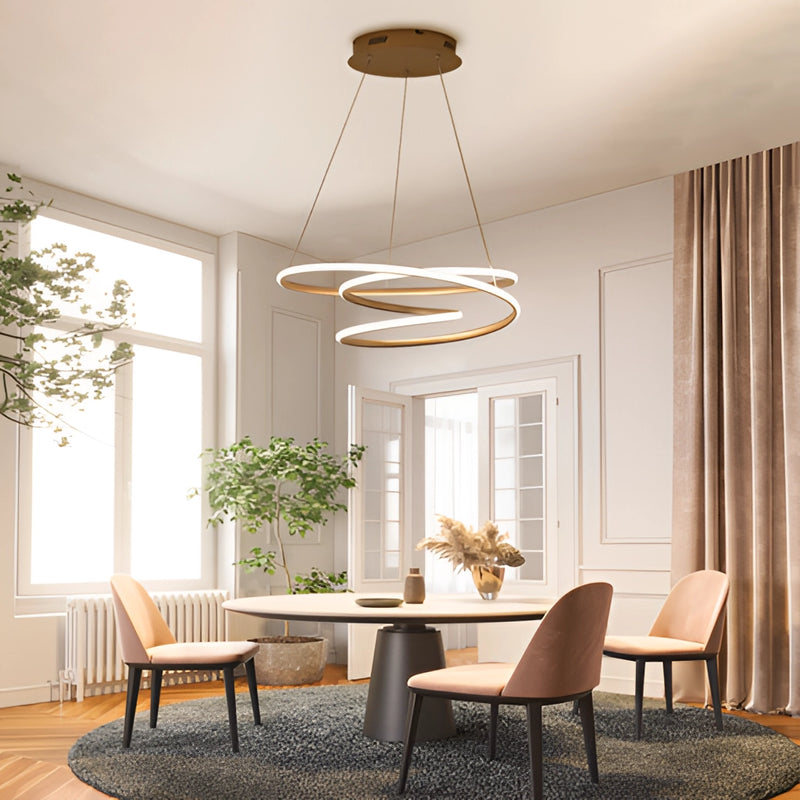 Spiral pendant light hanging above a wooden table in a room with elegant furniture, plants, and a window, providing warm illumination.