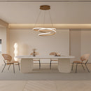 Elegant spiral pendant light with warm illumination hanging over a wooden table in a beige interior setting, with chairs and modern flooring visible.