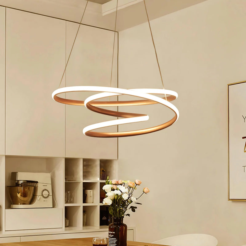 Elegant spiral pendant light with warm illumination hanging over a wooden table, surrounded by houseplants and flowerpots, enhancing a modern interior design.