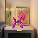 Crystal table lamp with touch-sensitive dimmable feature, showcasing a balloon dog design, placed on a wooden table amidst purple and pink flowers.