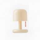 Dimmable ivory table lamp with touch switch on a wooden chair, emitting light in a room.