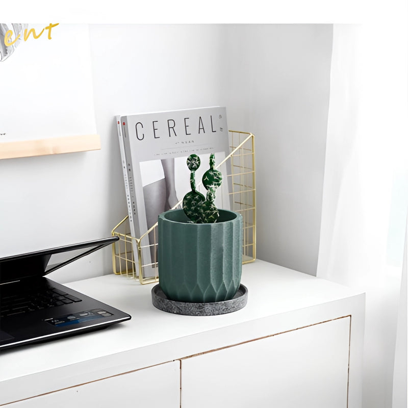 Textured ceramic polygon vase with a geometric design, featuring a houseplant, placed on a table beside a laptop and other computer devices.