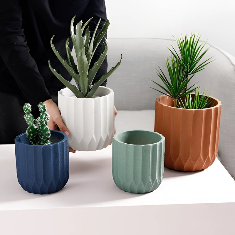 Textured white ceramic polygon vase with a geometric design, featuring green houseplants.