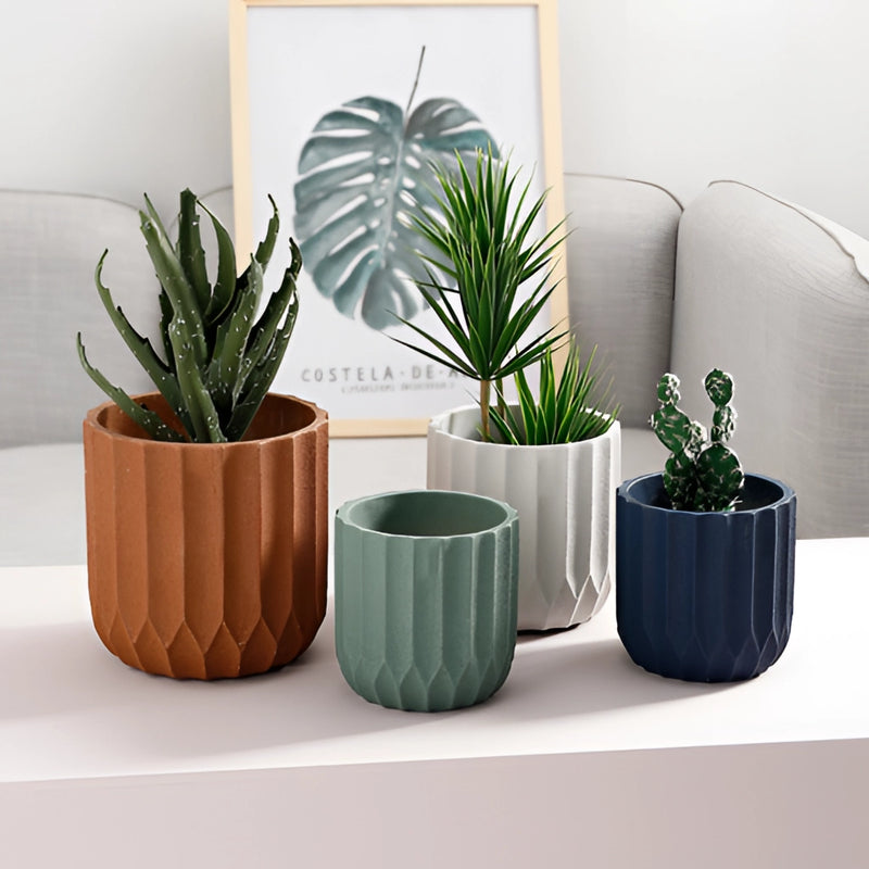 White textured ceramic polygon vase with a geometric design, featuring green houseplants in a cozy interior setting with a couch.