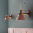 Elegant retro design wall light with a matt finish, featuring a metal lampshade, mounted on a wooden shelving unit against an orange tinted background.