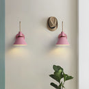Elegant retro design wall light with a matt finish, featuring a wood base and magenta tints, adorned with plant twigs, lighting a ceiling fixture, depicted in a still life photography setting.