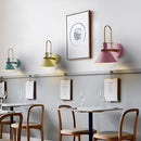 Elegant retro design wall light with a matt finish, displayed in an interior setting featuring white and yellow furnishings including a table, chairs, and shelving.