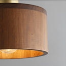 Walnut wood pendant lamp inspired by Japanese woodworking, featuring a cylindrical shade made from layers of stained hardwood and plywood, creating a warm, ambient light.