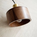 Walnut wood pendant lamp inspired by Japanese woodworking, featuring a rectangular and circular design, hanging from the ceiling as a light fixture.