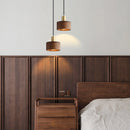 Walnut wood pendant lamp inspired by Japanese woodworking, hanging above a table in a well-designed interior with wood furniture and cabinetry.