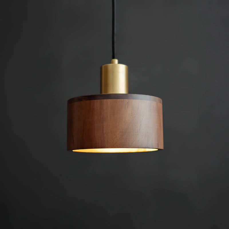 Walnut wood pendant lamp inspired by Japanese woodworking, featuring a cylindrical shape with metal accents, hanging from the ceiling.