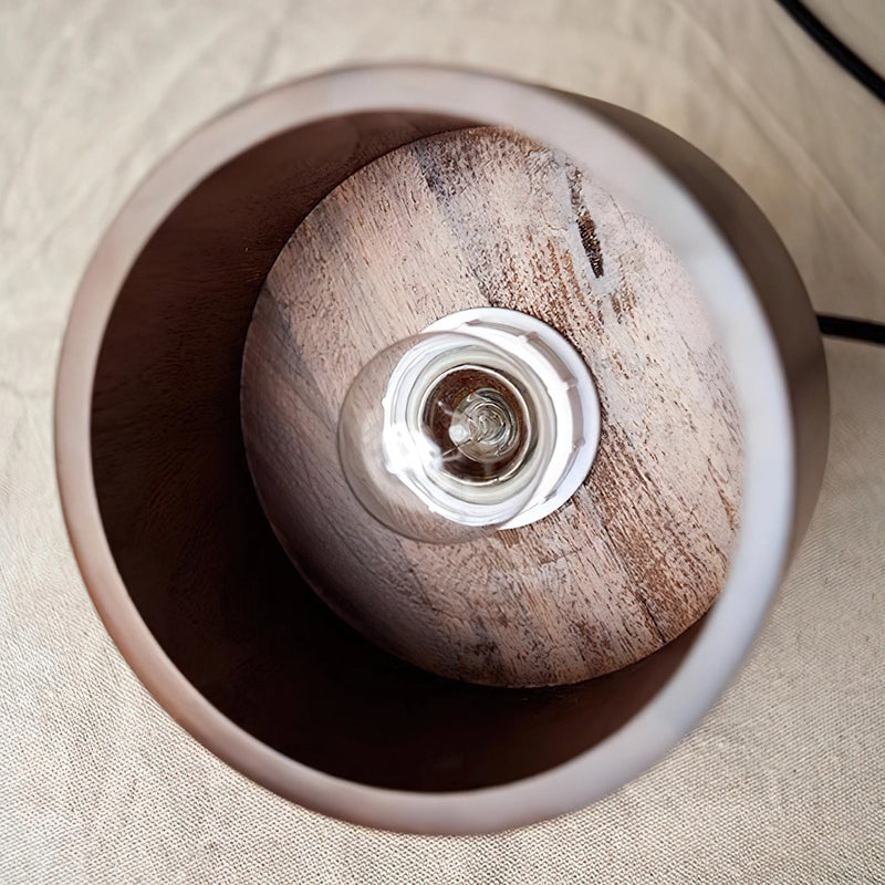 Walnut wood pendant lamp inspired by Japanese woodworking, featuring a spiral design and circular shape, suspended above a table.