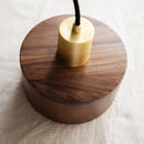 Walnut wood pendant lamp inspired by Japanese woodworking, featuring a circular hardwood design with a varnished finish, suspended from the ceiling.