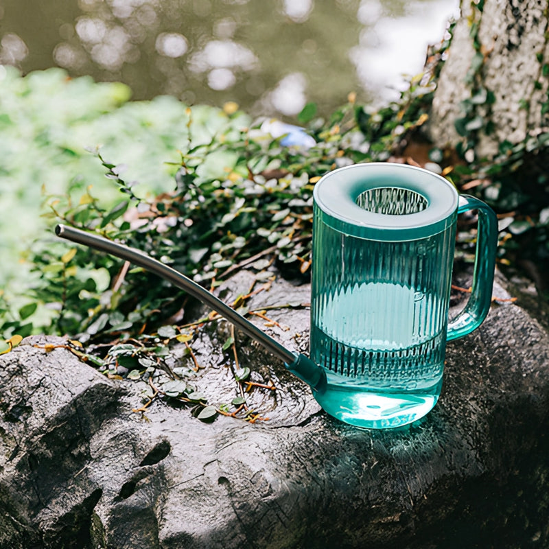 Blue aluminum watering can with an extended spout, placed on grass, designed for accurate water delivery.