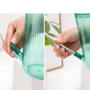 Hand demonstrating the use of a watering can with extended spout for accurate water delivery.