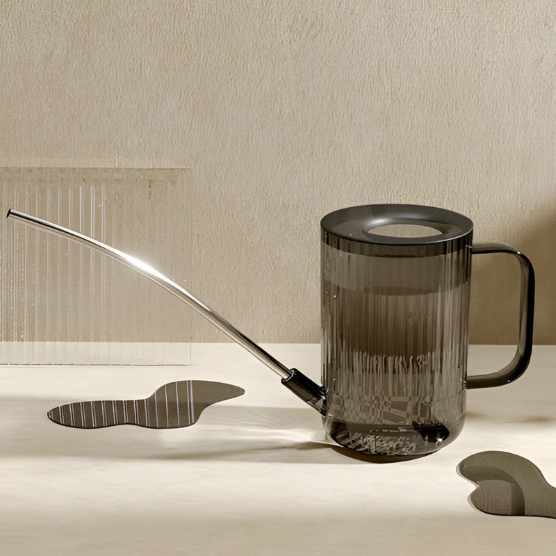 Stainless steel watering can with extended spout on a wooden table, designed for precise water delivery to plants.