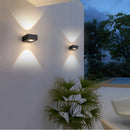 Modern waterproof black UFO wall light mounted on a wooden wall beside green indoor plants, highlighting the sleek and contemporary design.