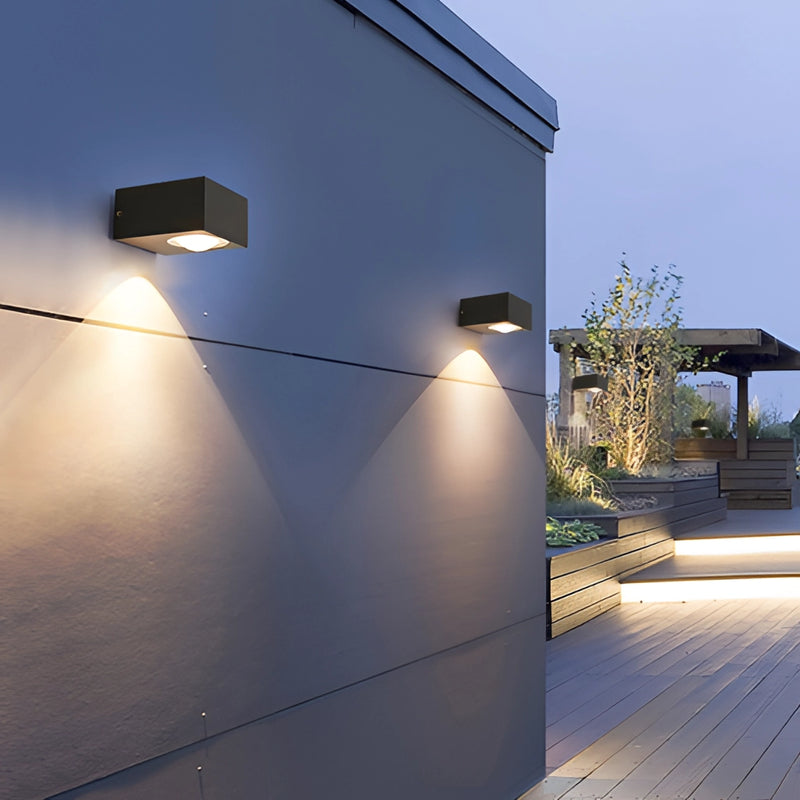 Black UFO-shaped waterproof wall light mounted on a building facade under a clear sky during daytime.