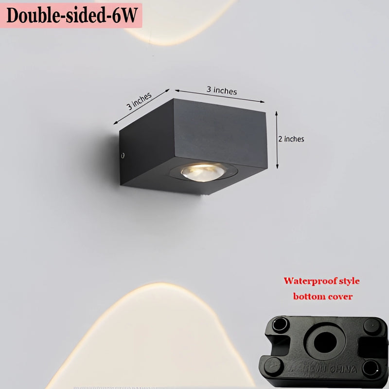 Double-sided waterproof black UFO wall light mounted on a wooden surface, featuring a circular design and electronic elements.