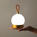 Amber-colored waterproof LED lamp designed as a blimp, featuring gesture control and a quick charging cordless design, displayed on a wooden nightstand under a ceiling light fixture.