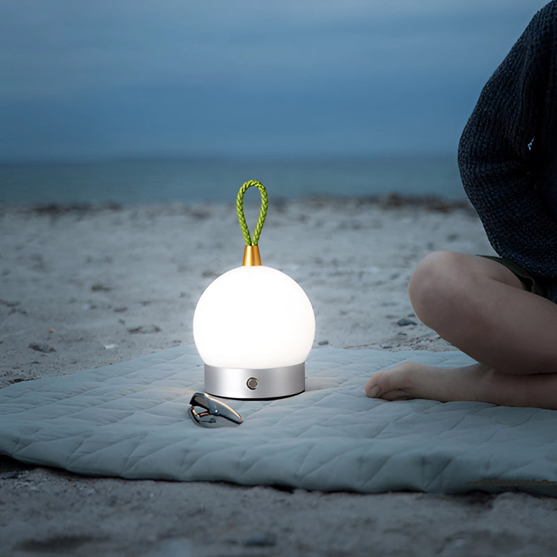 Cordless waterproof LED lamp blimp floating over a serene beach landscape, illuminated by morning sunlight with a clear azure sky and horizon in the background.