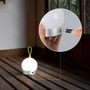 Cordless nightstand table light featuring a waterproof LED lamp blimp, placed on a wooden table with a wall and flooring visible in the background. The design includes both rectangular and circular elements.