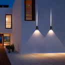 Pyramid-shaped LED wall sconce mounted on a wooden exterior near a window, providing a warm light that enhances the building's facade.